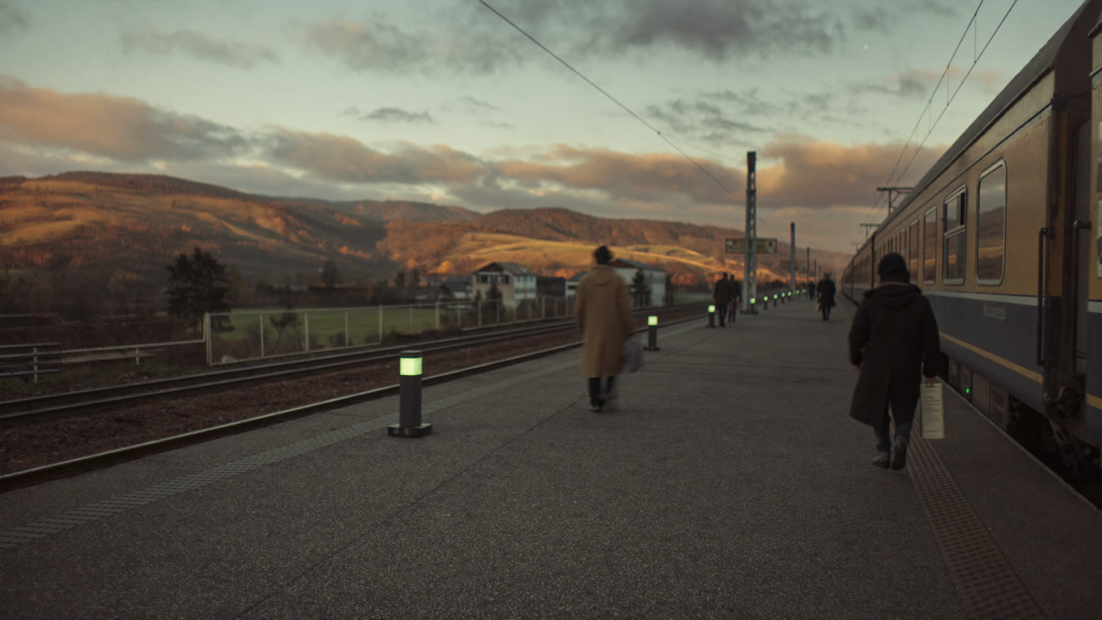 Frontalieri in attesa del treno sulla banchina di una stazione di confine all'alba