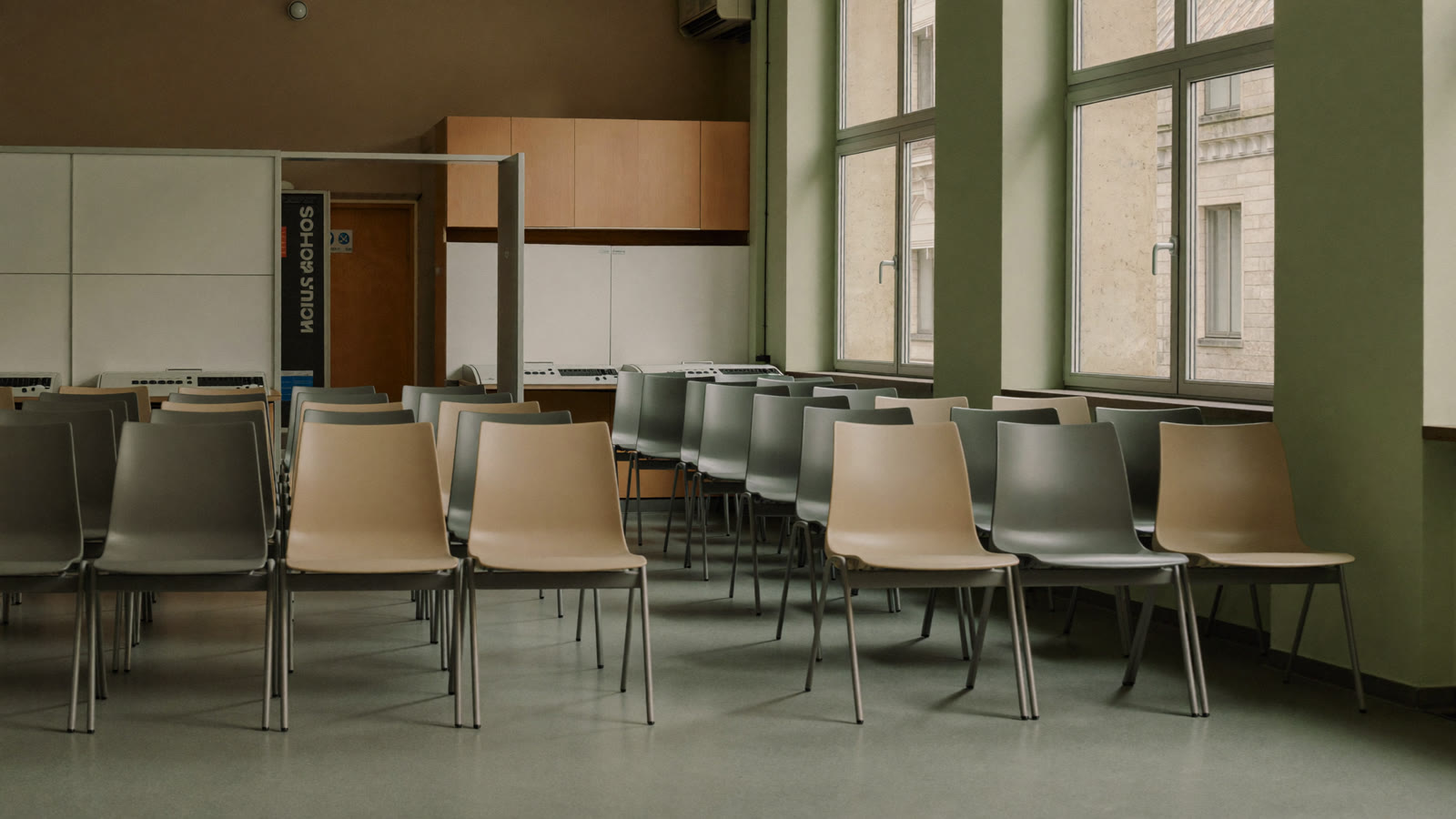 Salle d'attente silencieuse d'une agence de l'emploi public, avec des rangées de chaises et de postes informatiques sous une lumière naturelle douce.